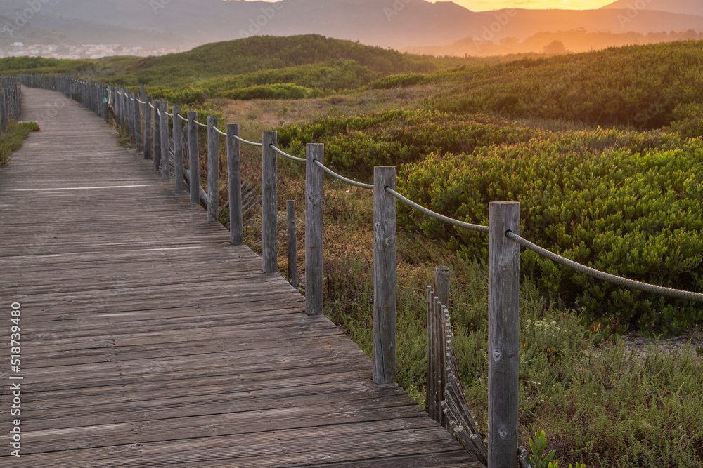 Sunrise view of a wooden walkway on the dunes of a beach