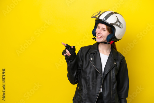 Young English woman with a motorcycle helmet isolated on yellow background pointing finger to the side and presenting a product © luismolinero