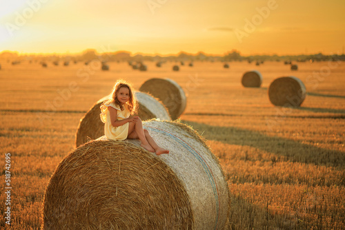 Fotografiet beautiful little girl on a picnic in a field near a stack of dry hay, portrait i