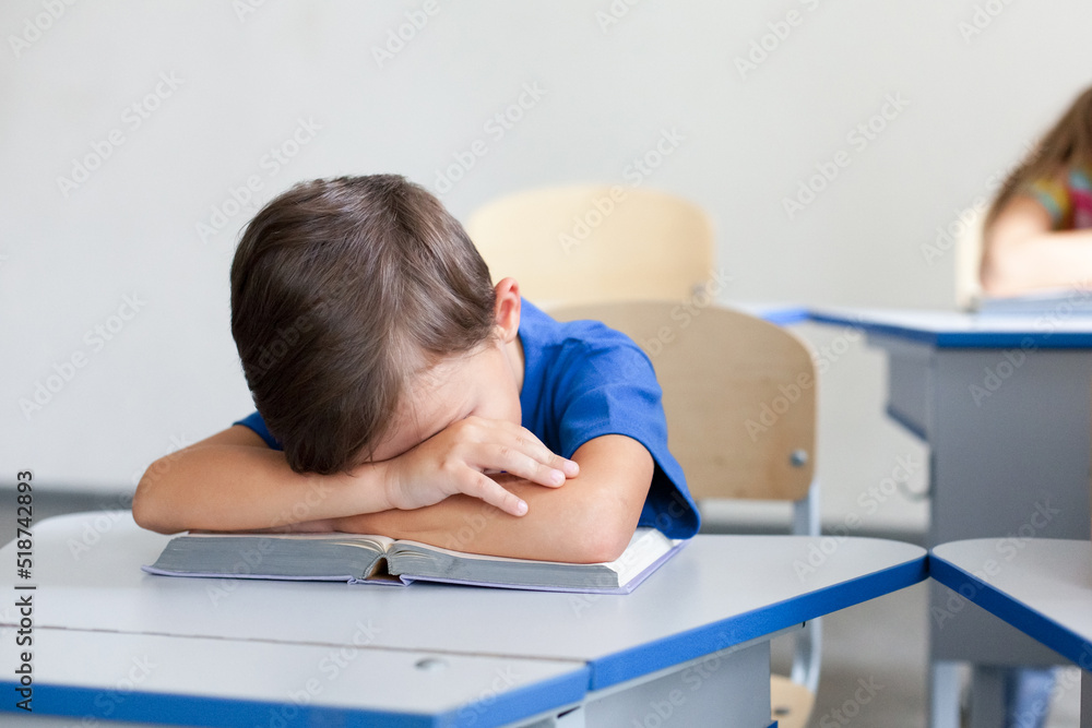 School child sleeping on boring lesson. Tired pupil learning to read book. Sleepy kid sitting at desk in classroom in elementary college. Primary student back to school in early morning School child sleeping on boring lesson. Tired pupil learning to read book. Sleepy kid sitting at desk in classroom in elementary college. Primary student back to school in early morning