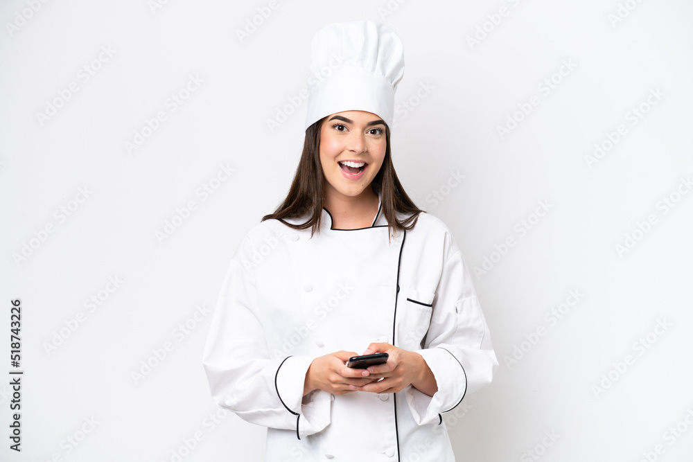 Young Brazilian chef woman isolated on white background surprised and sending a message Young Brazilian chef woman isolated on white background surprised and sending a message