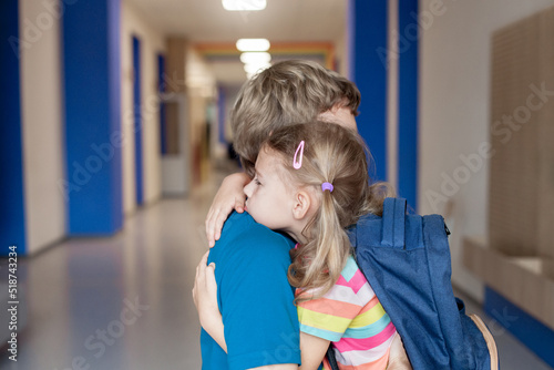 Upset schoolchild hugging father. Stressed kid and parent. First day at school. Concept of back to school, support, protection, togetherness, empathy, parenting. Authentic lifestyle moment