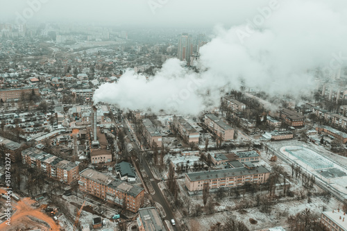 Industrial smoke from a chimney flies over the city, polluting the atmosphere - aerial drone shot. Industrial air pollution by production emissions in Kharkiv.