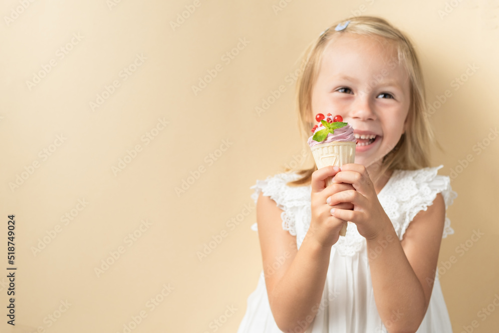 Beautiful little caucasian girl with blonde hair in a white dress enjoying berry flavored waffle cone ice cream on the beige background Beautiful little caucasian girl with blonde hair in a white dress enjoying berry flavored waffle cone ice cream on the beige background