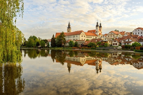 Telc with historical buildings, church and a tower. Buildings in water reflection.