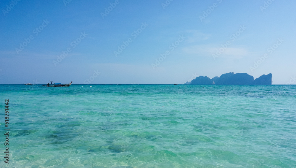 Tropical seascape with a long-tail boat, island, turquoise water and blue sky, Koh Phi Phi, Thailand