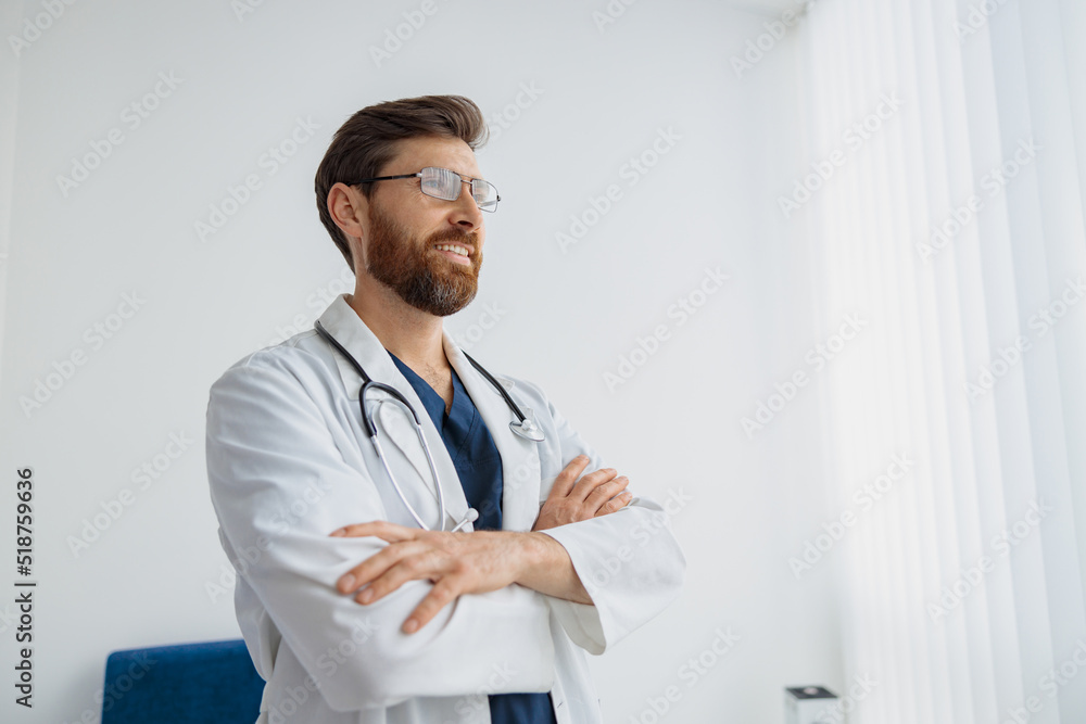 Portrait of smiling doctor in glasses standing in medicine clinic hall and looking away Portrait of smiling doctor in glasses standing in medicine clinic hall and looking away