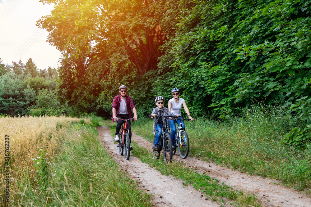 Naklejka premium family riding a bike in the countryside at hot sunny day