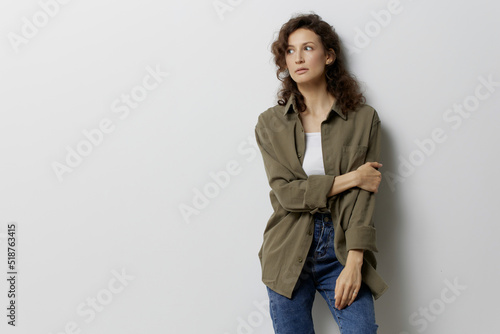Pensive curly beautiful woman in casual khaki green shirt cross hands think about problems in relationships posing isolated on over white background. People Emotions Lifestyle concept. Copy space