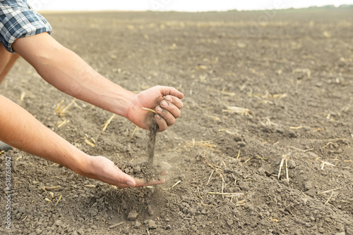Fotografie The farmer's hands hold a handful of fertile soil and pour it into the other hand