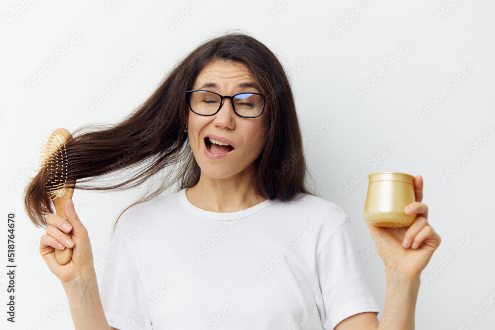 a beautiful, funny woman makes a funny face standing with a wooden comb in her hands and holding a golden jar of hair cream in the palm of her hand a beautiful, funny woman makes a funny face standing with a wooden comb in her hands and holding a golden jar of hair cream in the palm of her hand