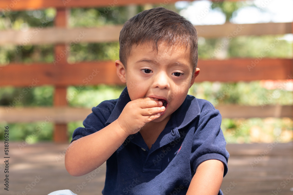 Portrait of a child with Down syndrome who eats candy in a peculiar way. Portrait of a child with Down syndrome who eats candy in a peculiar way.