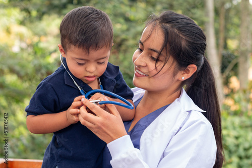 Doctor holding in her arms a child with Down syndrome to whom she lent her stethoscope. photo