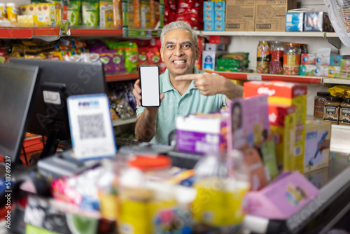 Portrait of happy man showing mobile phone screen at supermarket photo