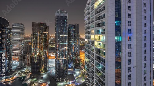 Tall residential buildings at JLT district aerial night timelapse, part of the Dubai multi commodities centre mixed-use district. Panoramic view to skyscrapers photo
