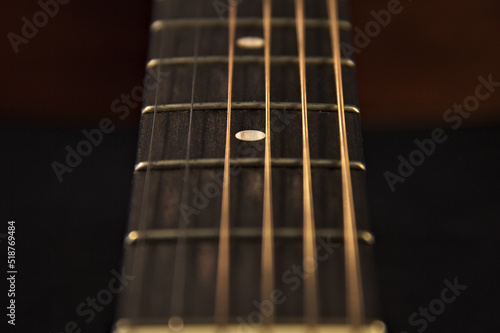 The neck of an acoustic six-string guitar. Close up.