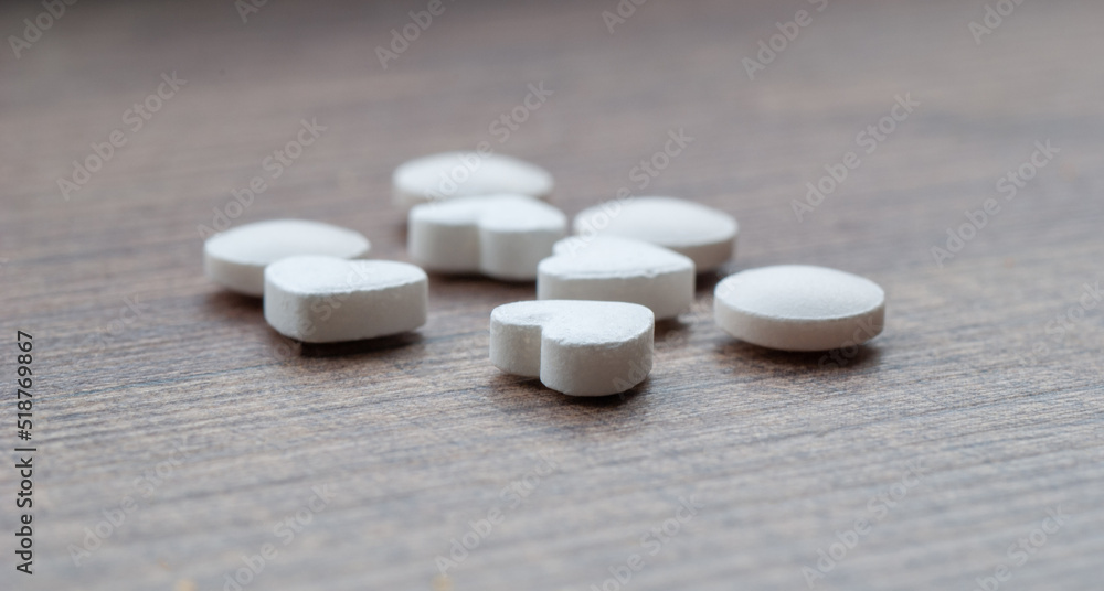 White pills in the shape of a heart on the surface White pills in the shape of a heart on the surface