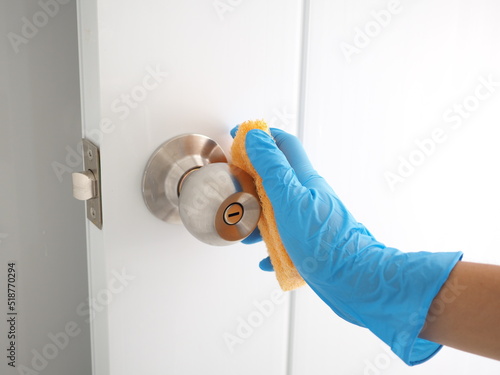 Woman wearing blue glove cleans the bathroom door lock with sponge. closeup photo blurred.