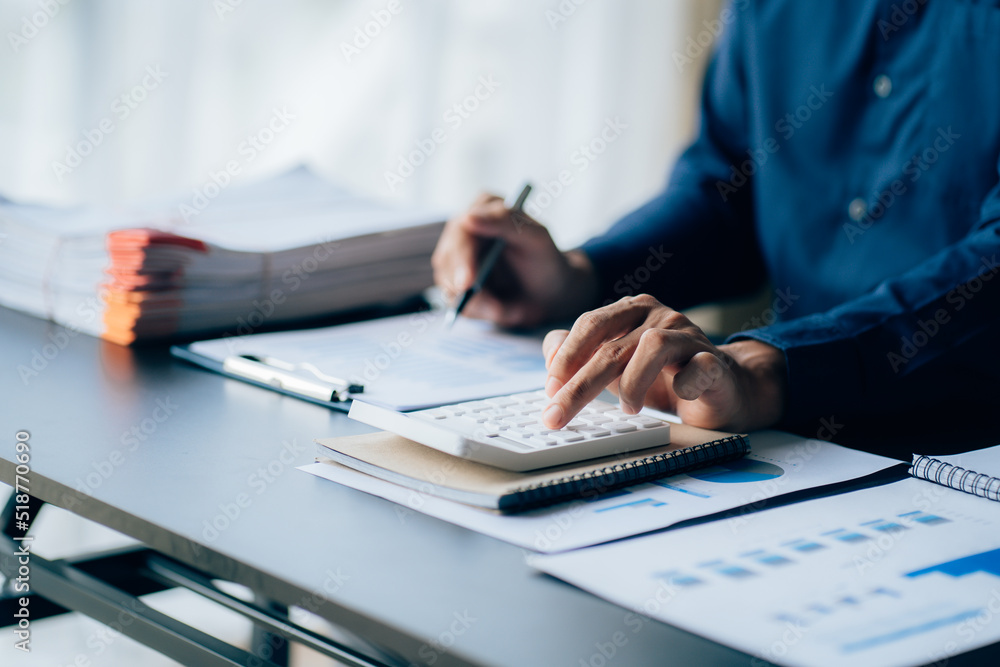The hands of a male businessman are analyzing and calculating the annual income and expenses in a financial graph that shows results To summarize balances overall in office The hands of a male businessman are analyzing and calculating the annual income and expenses in a financial graph that shows results To summarize balances overall in office
