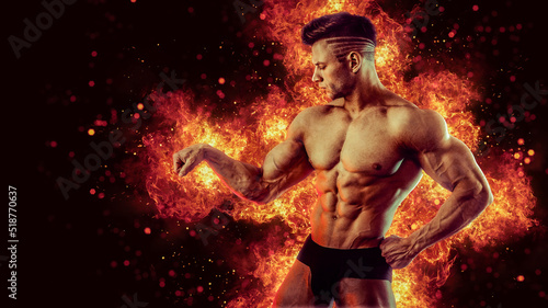 Brutal strong athletic Bodybuilder posing. Fire and spark explosion in the background.