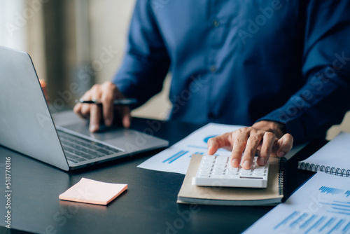 The hands of a male businessman are analyzing and calculating the annual income and expenses in a financial graph that shows results To summarize balances overall in office