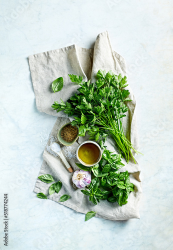 Simple arrangement of fresh herbs, olive oil, sea slat, garlic and black pepper on linen dish towel. Mediterranean-style cuisine. Flat lay