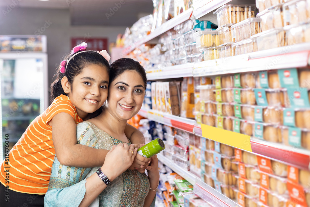 Happy mother and daughter reading product information while shopping at supermarket