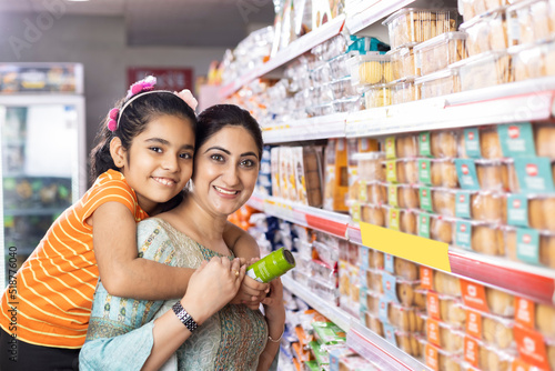 Photography Happy mother and daughter reading product information while shopping at supermar