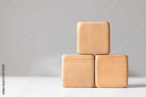Stacked wooden blocks form a pyramid staircase on a white tabletop with a gray background.Concept of success, growth, victory, foundation work, strength, development or top ranking.Free space for text