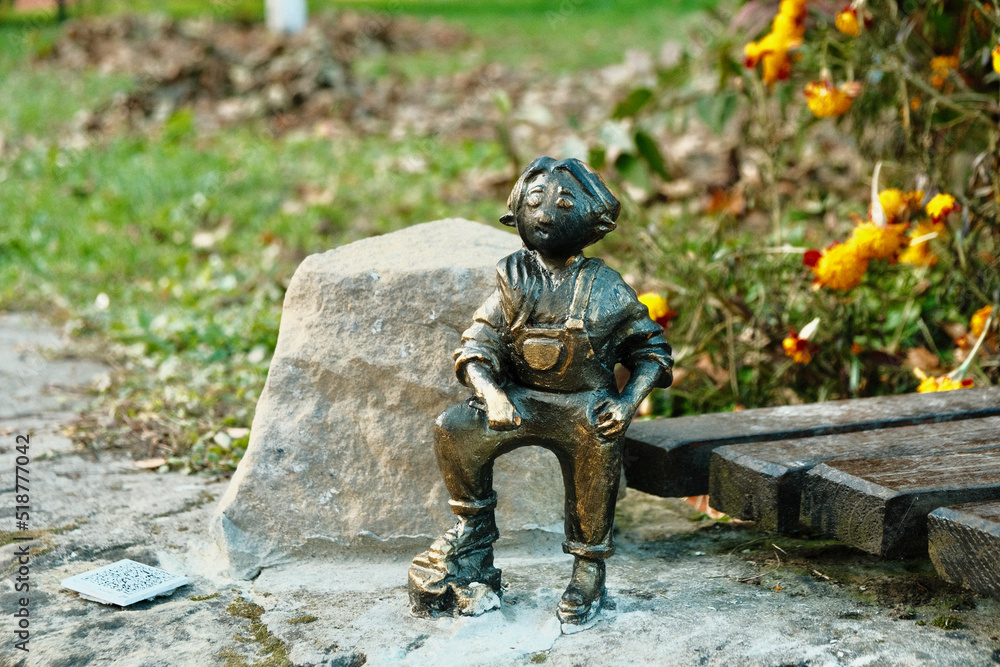 Miniature sculpture of a boy. Iron child on asphalt. Iron statue of a child