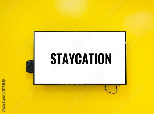 Staycation note on television against yellow wall