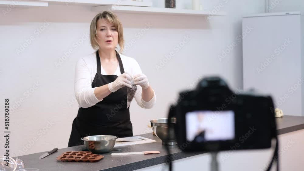 Blogger pastry chef makes a video lesson about cooking a cake. young woman in an apron in the white kitchen. Online broadcast, the author leads a blog or course about cooking Blogger pastry chef makes a video lesson about cooking a cake. young woman in an apron in the white kitchen. Online broadcast, the author leads a blog or course about cooking