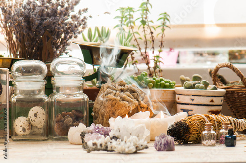 Cozy space with candles, crystals, herbs, and plants. Alternative medicine, herbal medicine, aromatherapy or esoteric background with incense smoke. photo