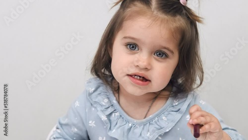 Close-up face of a cute attractive little girl with big eyes. In room. White background.