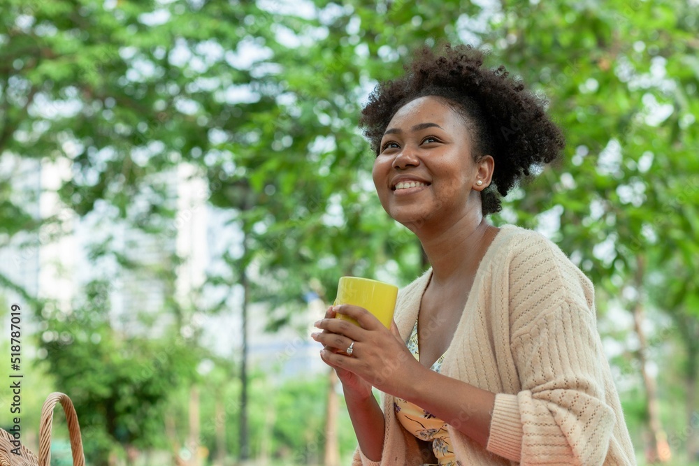 Beautiful African American woman enjoying music with headphones in the park. Beautiful African American woman enjoying music with headphones in the park.