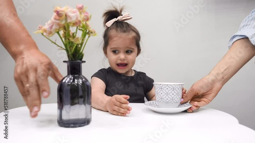 Cute little girl is drinking tea at home. On a white background.