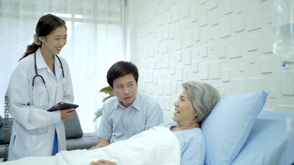 Senior Asian female patient resting on the medical bed in hospital and talking to her son. Senior Asian female patient resting on the medical bed in hospital and talking to her son.