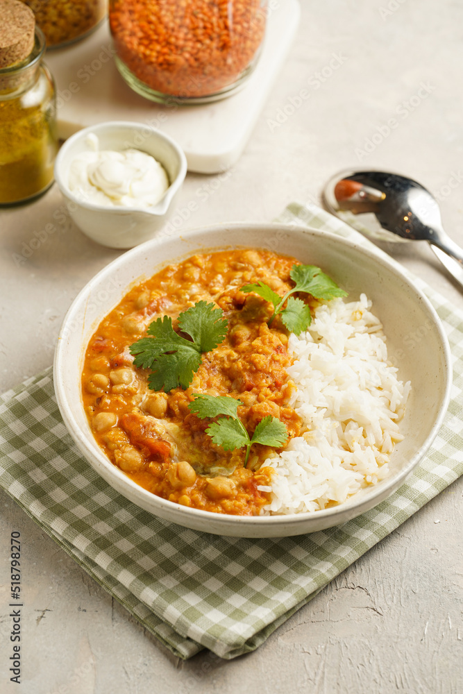 Indian red lentil curry with chickpeas, white rice and fresh cilantro - chana dal - in a white bowl on a green checkered kitchen towel Indian red lentil curry with chickpeas, white rice and fresh cilantro - chana dal - in a white bowl on a green checkered kitchen towel