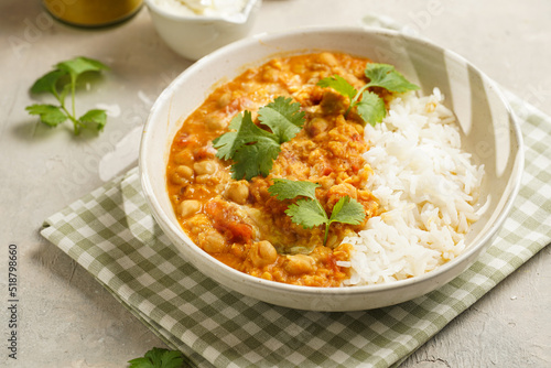 Indian red lentil curry with chickpeas, white rice and fresh cilantro - chana dal - in a white bowl on a green checkered kitchen towel