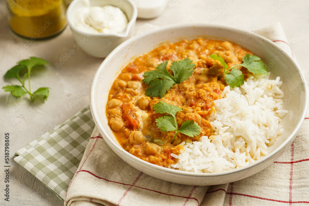 Indian red lentil curry with chickpeas, white rice and fresh cilantro - chana dal - in a white bowl on a green checkered kitchen towel Indian red lentil curry with chickpeas, white rice and fresh cilantro - chana dal - in a white bowl on a green checkered kitchen towel