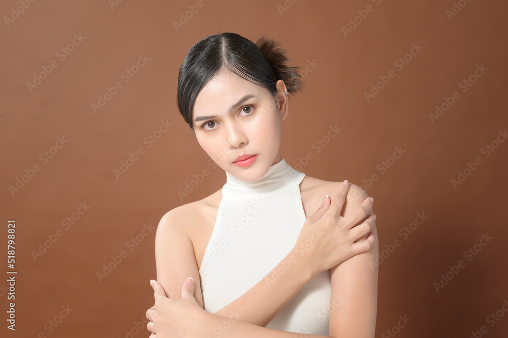 A young woman with beautiful face smiling, touching her skin over brown background , beauty skin care concept A young woman with beautiful face smiling, touching her skin over brown background , beauty skin care concept