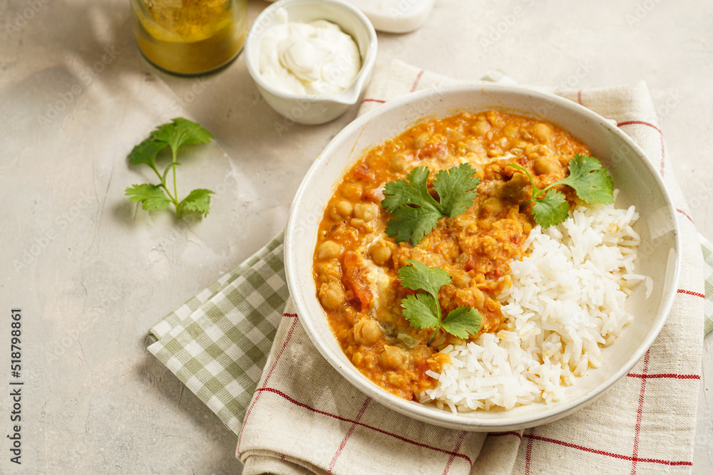 Indian red lentil curry with chickpeas, white rice and fresh cilantro - chana dal - in a white bowl on a green checkered kitchen towel