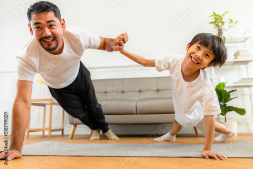 Young asian parents with child meditating at home isolated in room. Family, sport, yoga concept.