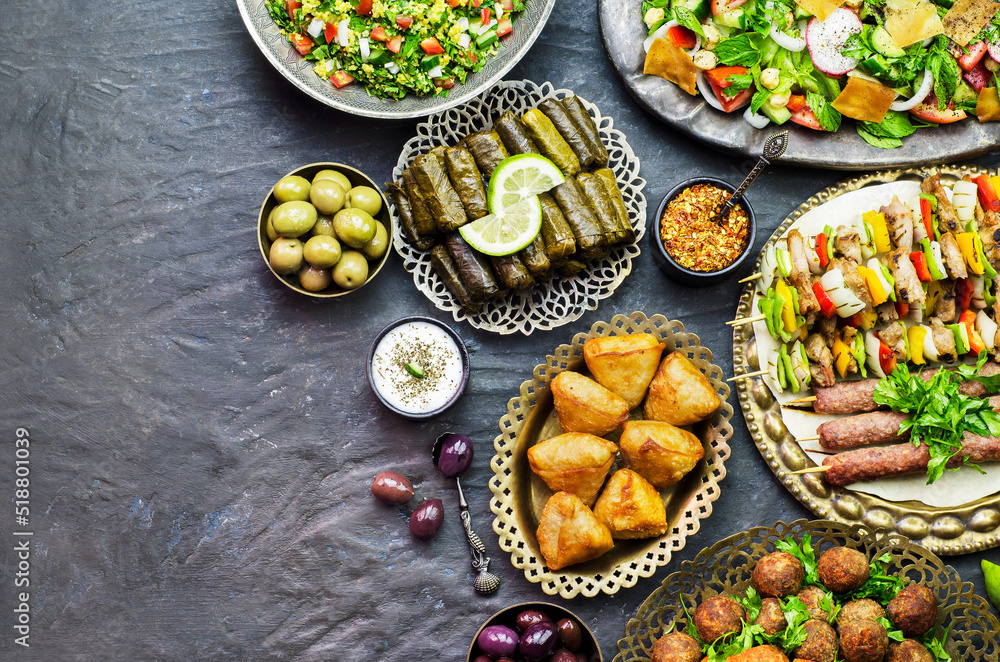 Arabic cuisine;Assorted of middle eastern traditional dishes. Stuffed vine leaves,olives, kibbeh, shish tawook, flafel, sambusak, tabbouleh and fattoush salad. Halal food. Top view with copy space. Arabic cuisine;Assorted of middle eastern traditional dishes. Stuffed vine leaves,olives, kibbeh, shish tawook, flafel, sambusak, tabbouleh and fattoush salad. Halal food. Top view with copy space.