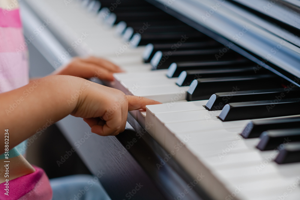 Obraz premium Hands of little girl playing piano, selective focus
