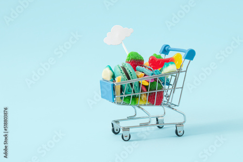 Creative Halloween sopping cart.concept many sweets for children in one place, a delicious junk snack. Flat lay, pastel blue background.