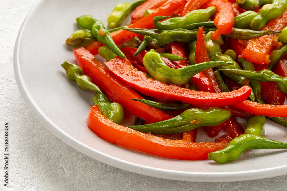 Stir-fry rat tail radish dish with red bell pepper on a plate. Vegan cuisine meal. Stir-fry rat tail radish dish with red bell pepper on a plate. Vegan cuisine meal.