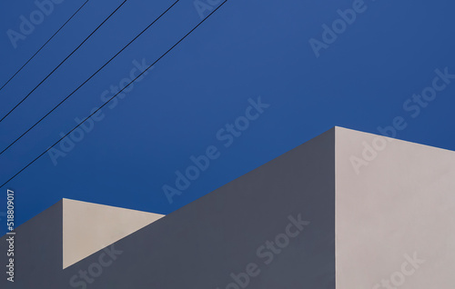 Sunlight and shadow on surface of beige building with electric power lines on blue clear sky  Minimal geometric architecture background concept
