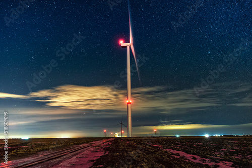 Night photo of a windmill and stars with abstract lighting. Wind turbine at night against the background of stars. Environment and Renewable Energy