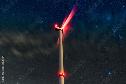 Night photo of a windmill and stars with abstract lighting. Wind turbine at night against the background of stars. Environment and Renewable Energy